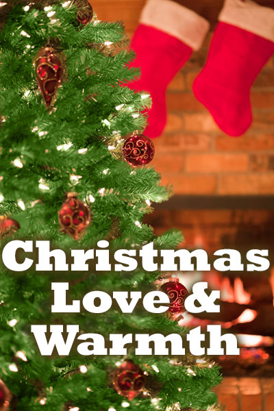 A Christmas tree with lights and ornaments. A brick fireplace is in the background, with a cozy fire lit inside of it, and red and white stockings hanging on the mantle. The words Christmas Love and Warmth are at the bottom.